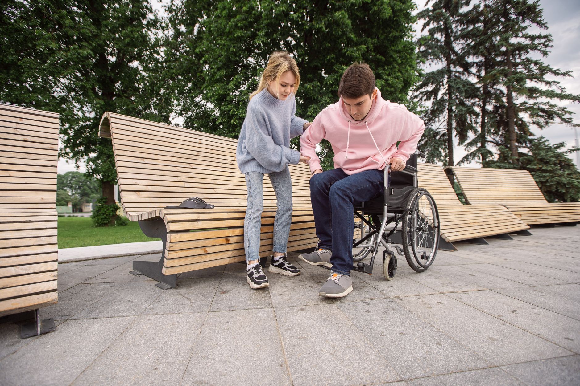 A support worker in a warm one-to-one conversation with a participant on a park bench